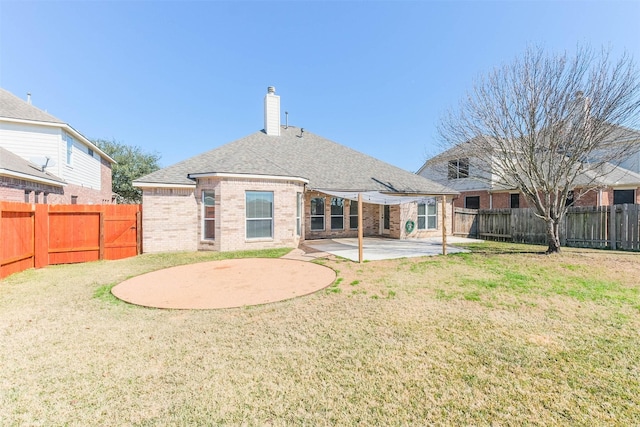 back of property featuring a lawn, a patio, a fenced backyard, a chimney, and brick siding