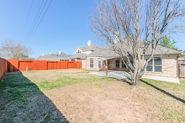 back of property featuring a patio area, brick siding, a yard, and a fenced backyard