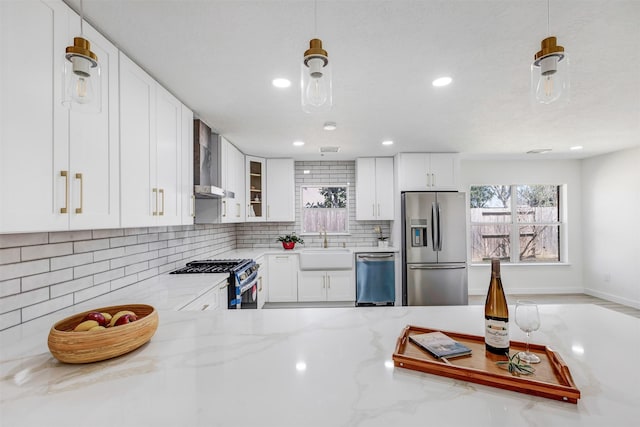 kitchen with stainless steel appliances, wall chimney range hood, backsplash, and white cabinetry