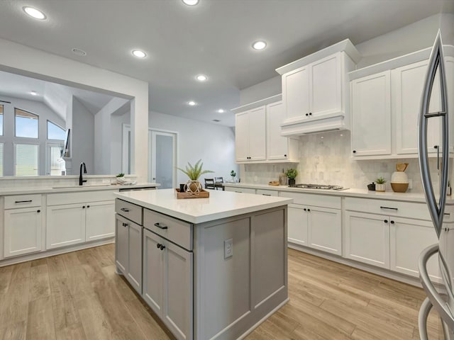 kitchen with gray cabinets, a sink, light wood-style floors, appliances with stainless steel finishes, and light countertops