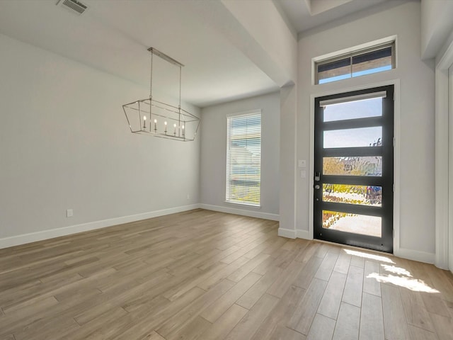 foyer entrance featuring visible vents, baseboards, an inviting chandelier, and light wood-style flooring