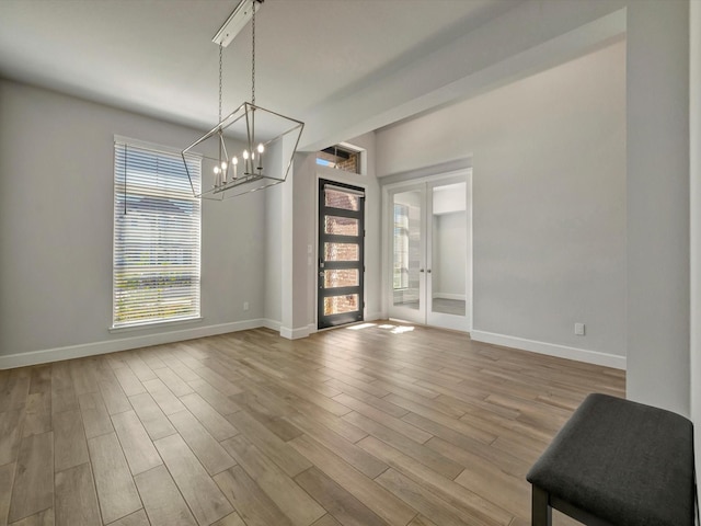 unfurnished dining area featuring a chandelier, baseboards, and wood finished floors