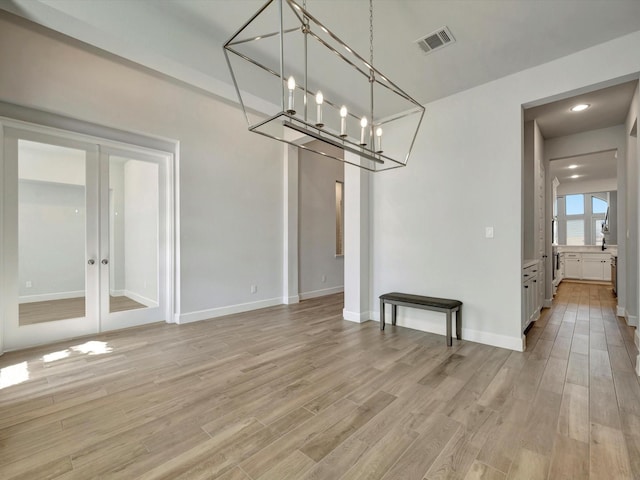 unfurnished dining area with light wood-style flooring, french doors, visible vents, and a chandelier