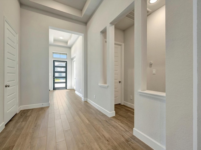 entrance foyer with a raised ceiling, wood finished floors, and baseboards