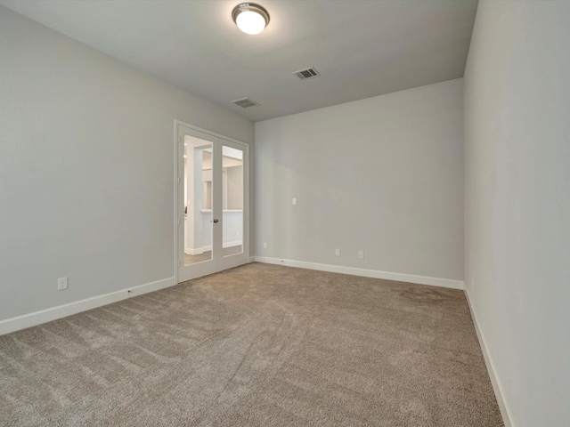 carpeted spare room with baseboards, visible vents, and french doors