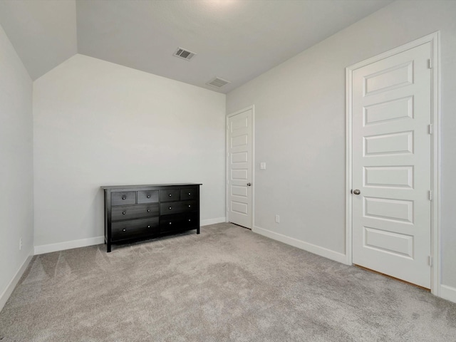 unfurnished bedroom featuring visible vents, baseboards, carpet, and vaulted ceiling