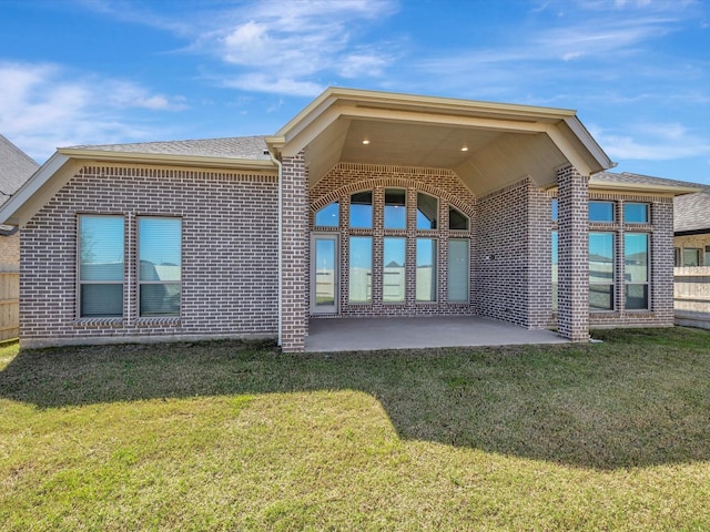 rear view of house with a patio, a lawn, and brick siding