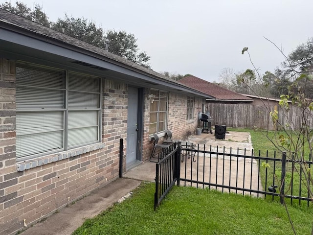 exterior space with fence, a patio, and brick siding