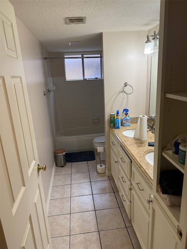 bathroom with double vanity, tile patterned flooring, toilet, and a textured ceiling