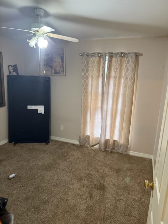 empty room featuring ceiling fan, carpet floors, and baseboards