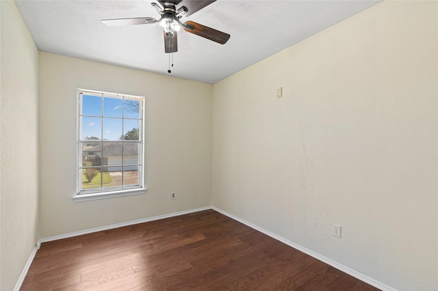 spare room with dark wood-style flooring, a ceiling fan, and baseboards