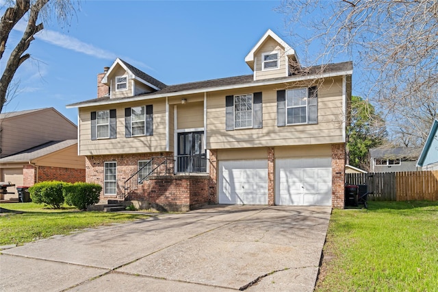 raised ranch featuring brick siding, fence, a garage, driveway, and a front lawn