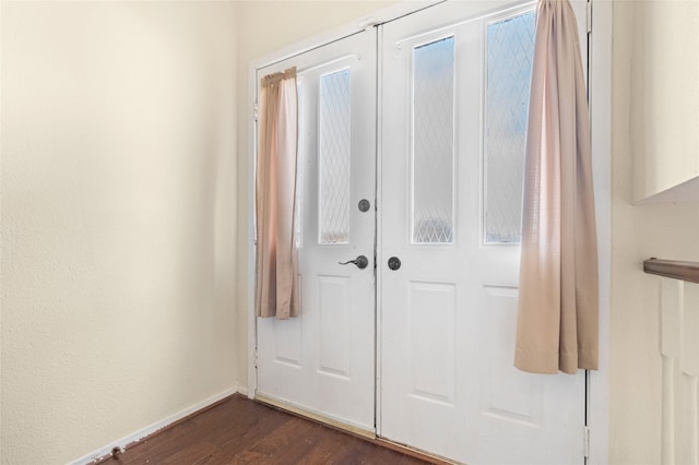 doorway with dark wood finished floors and baseboards