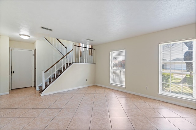 unfurnished room featuring light tile patterned floors, visible vents, and a healthy amount of sunlight