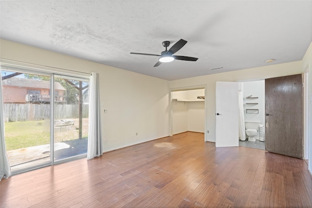 interior space featuring visible vents, ensuite bath, wood finished floors, access to outside, and a textured ceiling