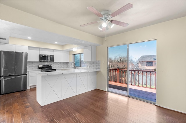 kitchen featuring stainless steel appliances, tasteful backsplash, light countertops, dark wood-type flooring, and white cabinets