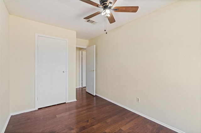 spare room featuring dark wood-style flooring, visible vents, ceiling fan, and baseboards