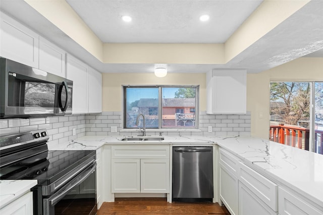 kitchen with stainless steel appliances, a sink, white cabinetry, and decorative backsplash