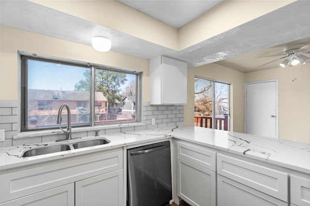 kitchen featuring light stone counters, tasteful backsplash, white cabinetry, a sink, and dishwasher