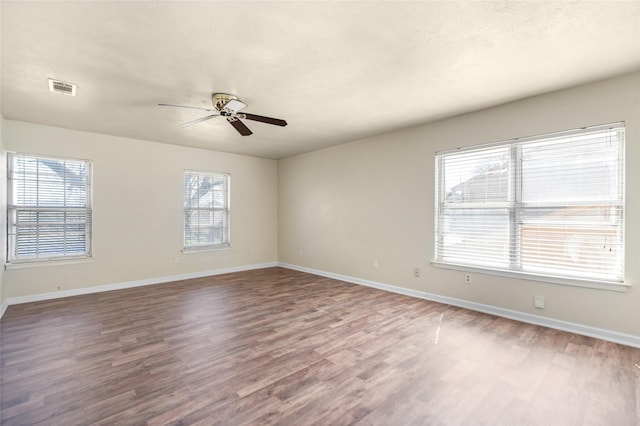 unfurnished room featuring baseboards, visible vents, ceiling fan, and wood finished floors