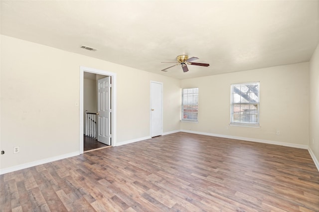 empty room featuring baseboards, visible vents, ceiling fan, and wood finished floors