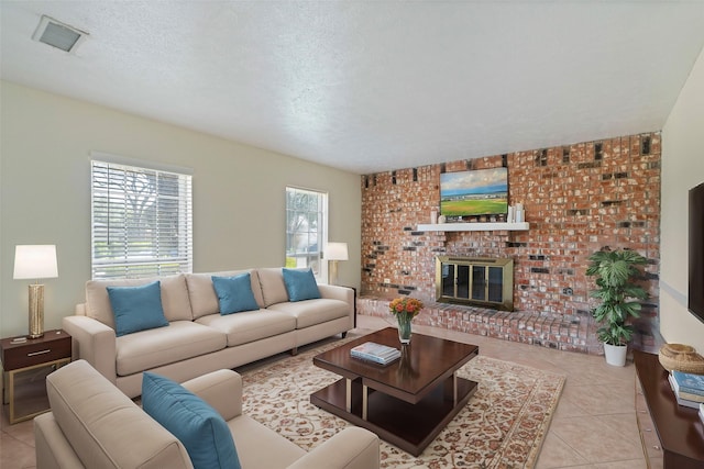 living room with a brick fireplace, visible vents, a textured ceiling, and light tile patterned floors