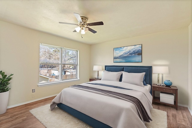 bedroom with wood finished floors, a ceiling fan, and baseboards