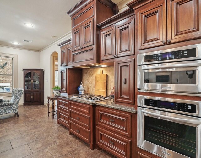 901 Longmire Rd Unit 17, Conroe, TX 77304 - kitchen with stainless steel appliances, arched walkways, crown molding, tasteful backsplash, and stone counters