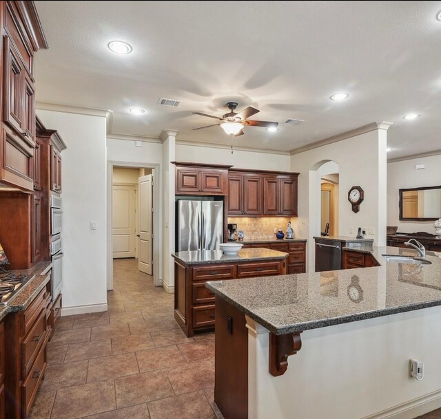 901 Longmire Rd Unit 17, Conroe, TX 77304 - kitchen with appliances with stainless steel finishes, a kitchen island, a sink, a ceiling fan, and crown molding