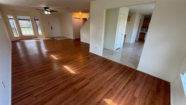 unfurnished living room with light wood-style floors, baseboards, and a ceiling fan