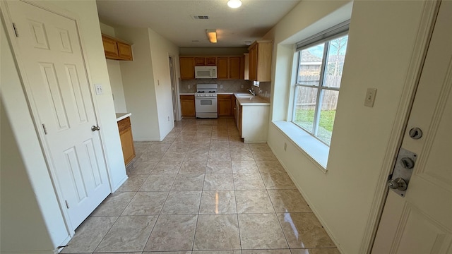 kitchen with white appliances, tasteful backsplash, visible vents, light countertops, and a sink