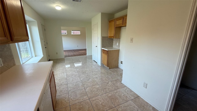 kitchen with brown cabinets, light countertops, decorative backsplash, and light tile patterned flooring