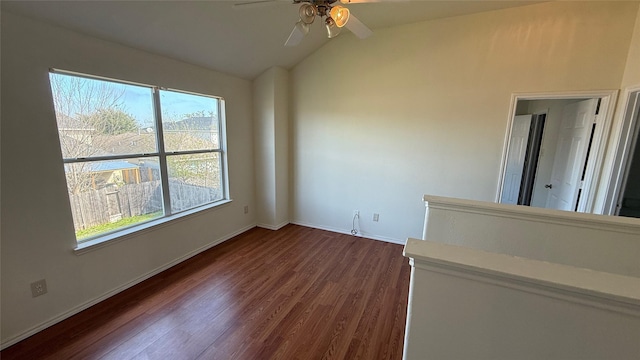 spare room featuring dark wood-style floors, baseboards, vaulted ceiling, and a ceiling fan