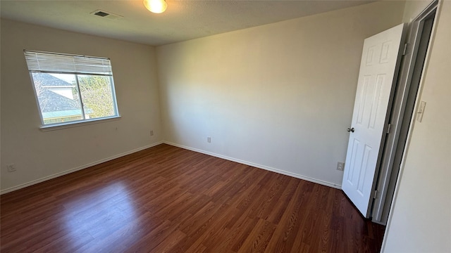 unfurnished bedroom with dark wood-style floors, visible vents, and baseboards