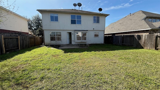 back of house with a fenced backyard and a lawn