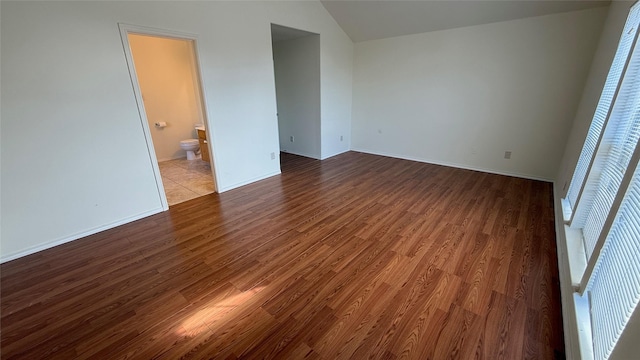 unfurnished room with baseboards, vaulted ceiling, and wood finished floors