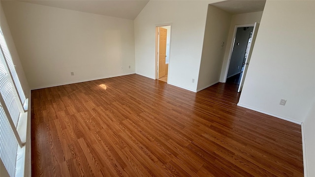 empty room featuring lofted ceiling, baseboards, and wood finished floors