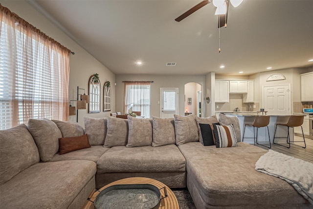 living room featuring arched walkways, ceiling fan, recessed lighting, visible vents, and light wood finished floors