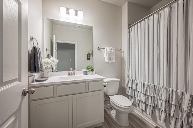 bathroom with toilet, a shower with shower curtain, wood finished floors, visible vents, and vanity