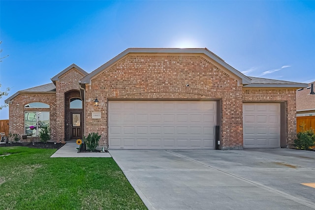 ranch-style home with brick siding, roof with shingles, an attached garage, a front yard, and driveway