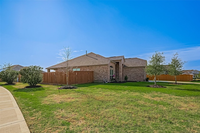 view of front of home with fence, a front lawn, and brick siding