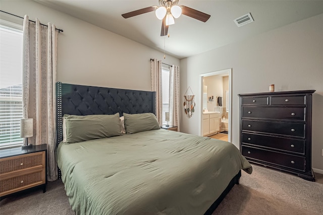 bedroom with carpet floors, visible vents, ceiling fan, and ensuite bathroom