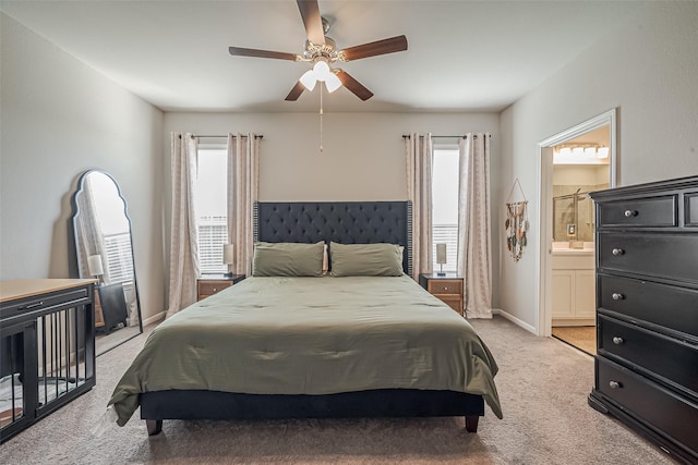 bedroom featuring light colored carpet, baseboards, multiple windows, and ensuite bath