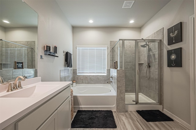 bathroom featuring a garden tub, visible vents, a shower stall, vanity, and wood finished floors