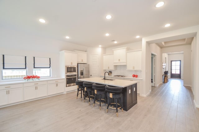 10711 Kingston Spring Dr, Missouri City, TX 77459 - kitchen featuring appliances with stainless steel finishes, a kitchen breakfast bar, a sink, decorative backsplash, and white cabinetry