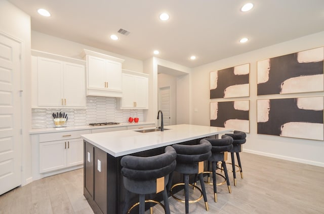 10711 Kingston Spring Dr, Missouri City, TX 77459 - kitchen with a sink, light countertops, tasteful backsplash, light wood-style flooring, and a center island with sink