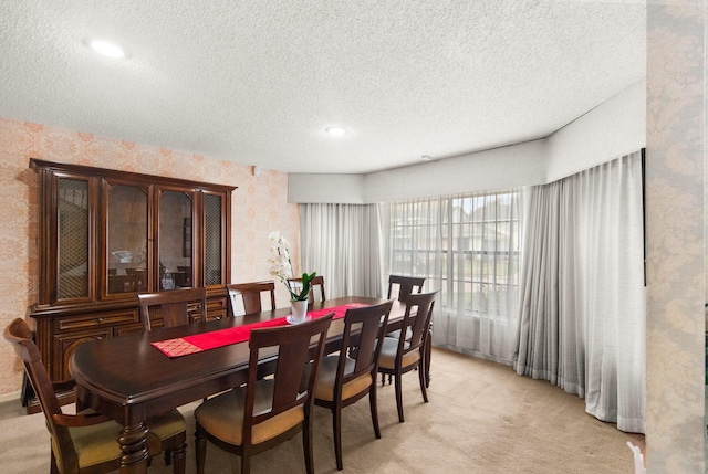 dining area featuring light colored carpet, a textured ceiling, and wallpapered walls