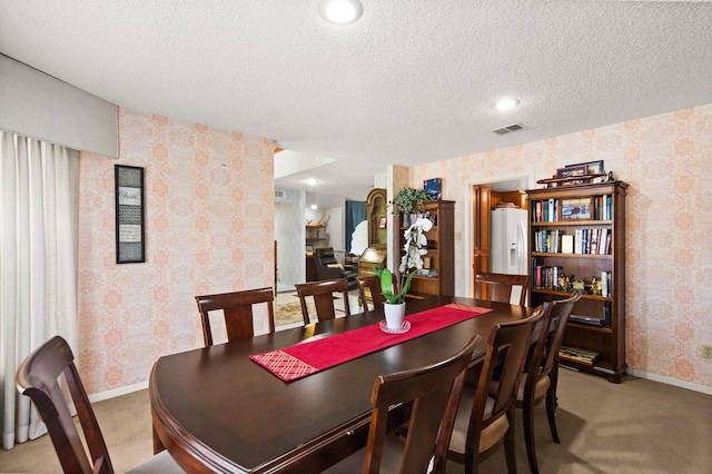 dining area featuring visible vents, light colored carpet, a textured ceiling, and wallpapered walls