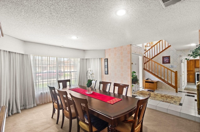 dining space with visible vents, light colored carpet, stairs, and wallpapered walls