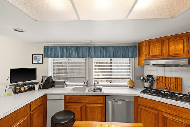 kitchen featuring under cabinet range hood, appliances with stainless steel finishes, light countertops, and a sink